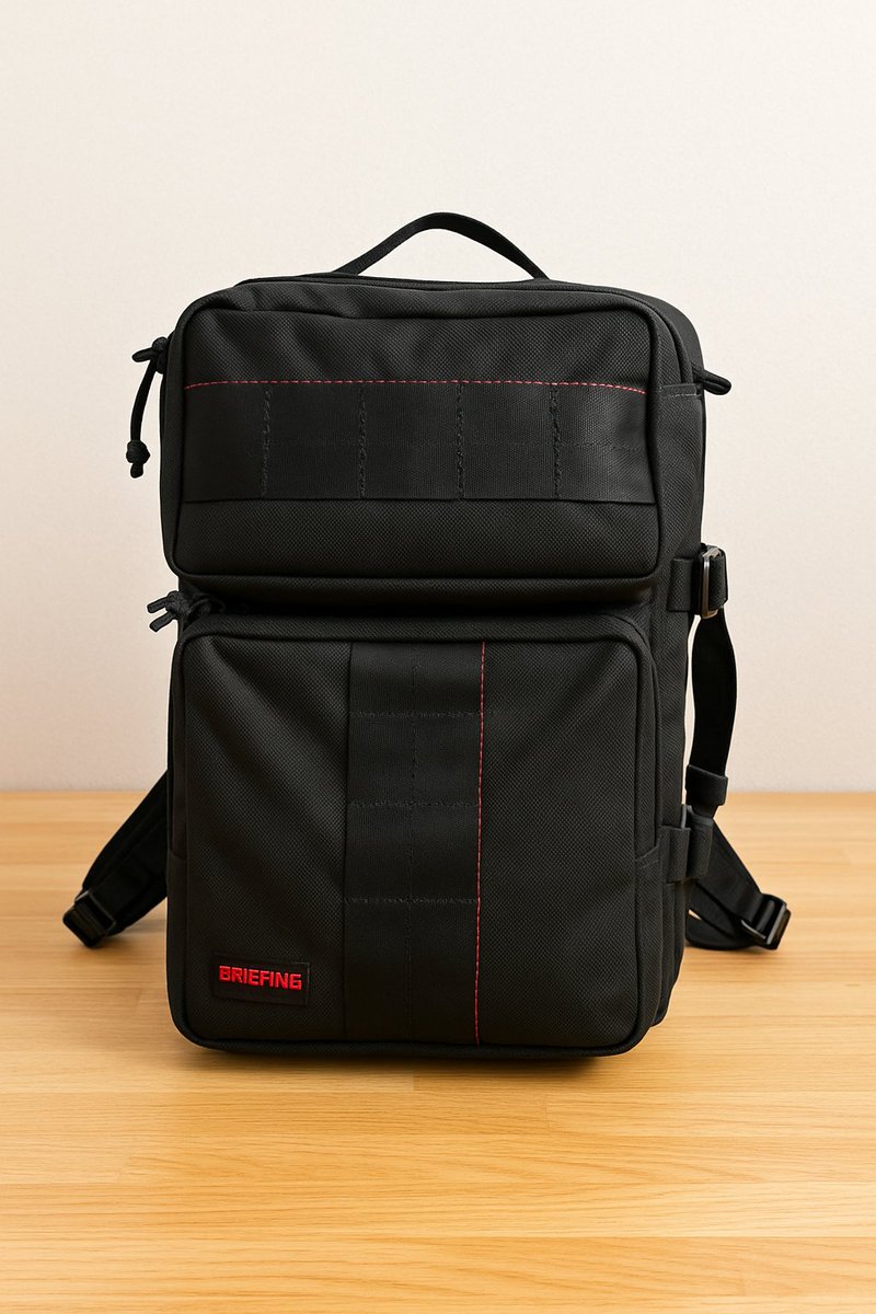 A black BRIEFING backpack on a wooden surface, highlighted by red stitching.